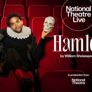 A black man in a Victorian outfit sits on theatre seats and holds a skull