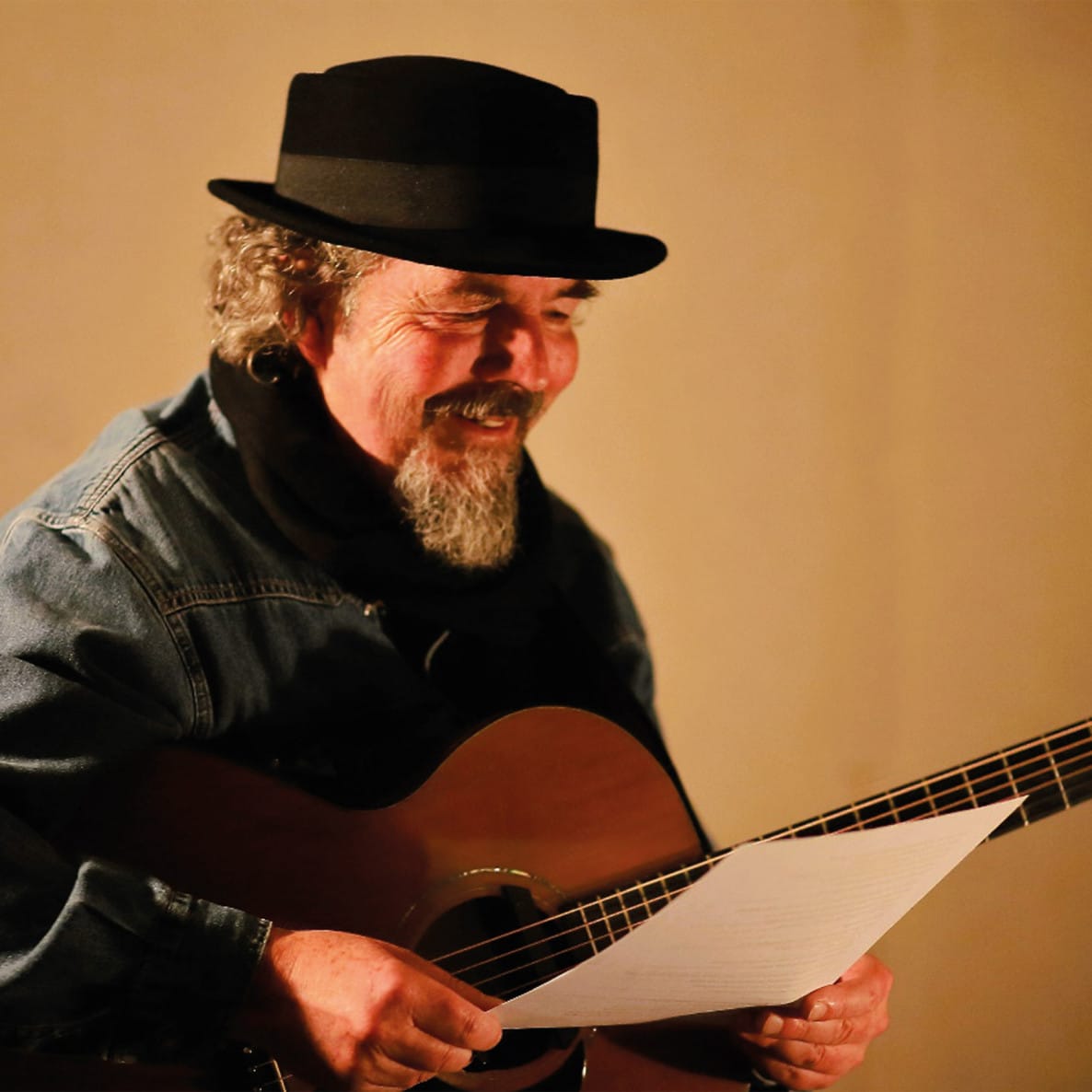 man with beard and hat plays guitar
