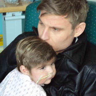 Man holding a child and kissing the child's head