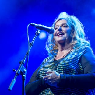 Woman singing into microphone with blue lighting
