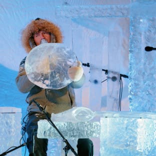Man in winter clothes playing an instrument made of ice