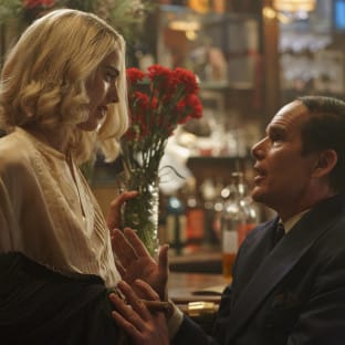 A blonde woman looking down at a man in a suit