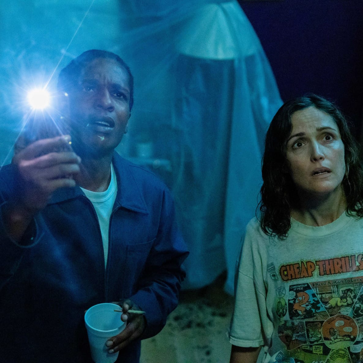 Two people in a dark room looking up holding a flashlight