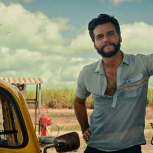 A man at a gas station leaning next to a car