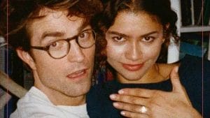 Woman with a ring on her finger smiling next to man with glasses